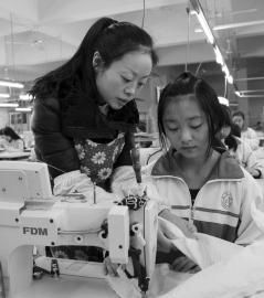 大英縣中等職業技術學校內，企業服裝技師正指導學生進行縫紉操作。